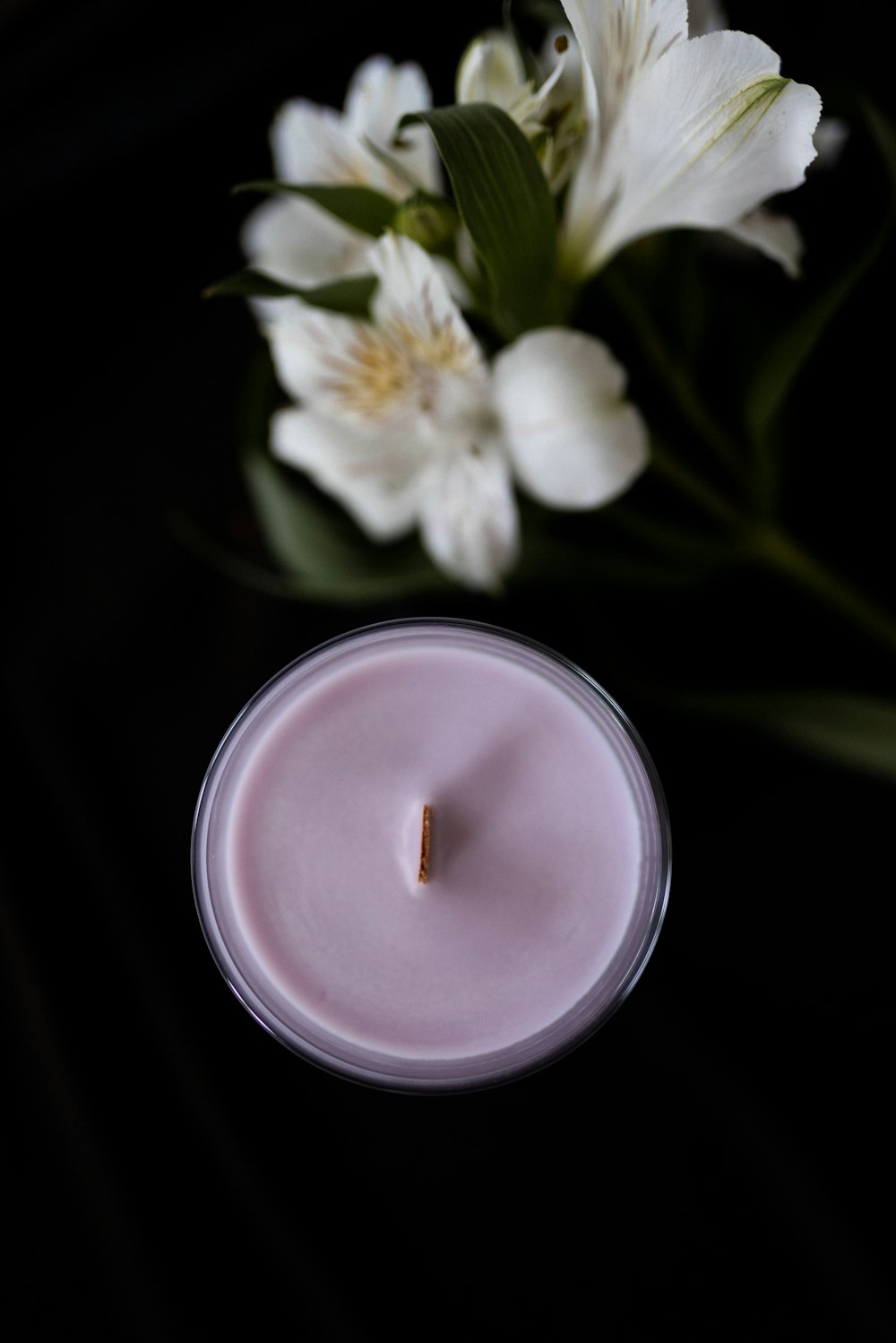 a white candle sitting next to a white flower