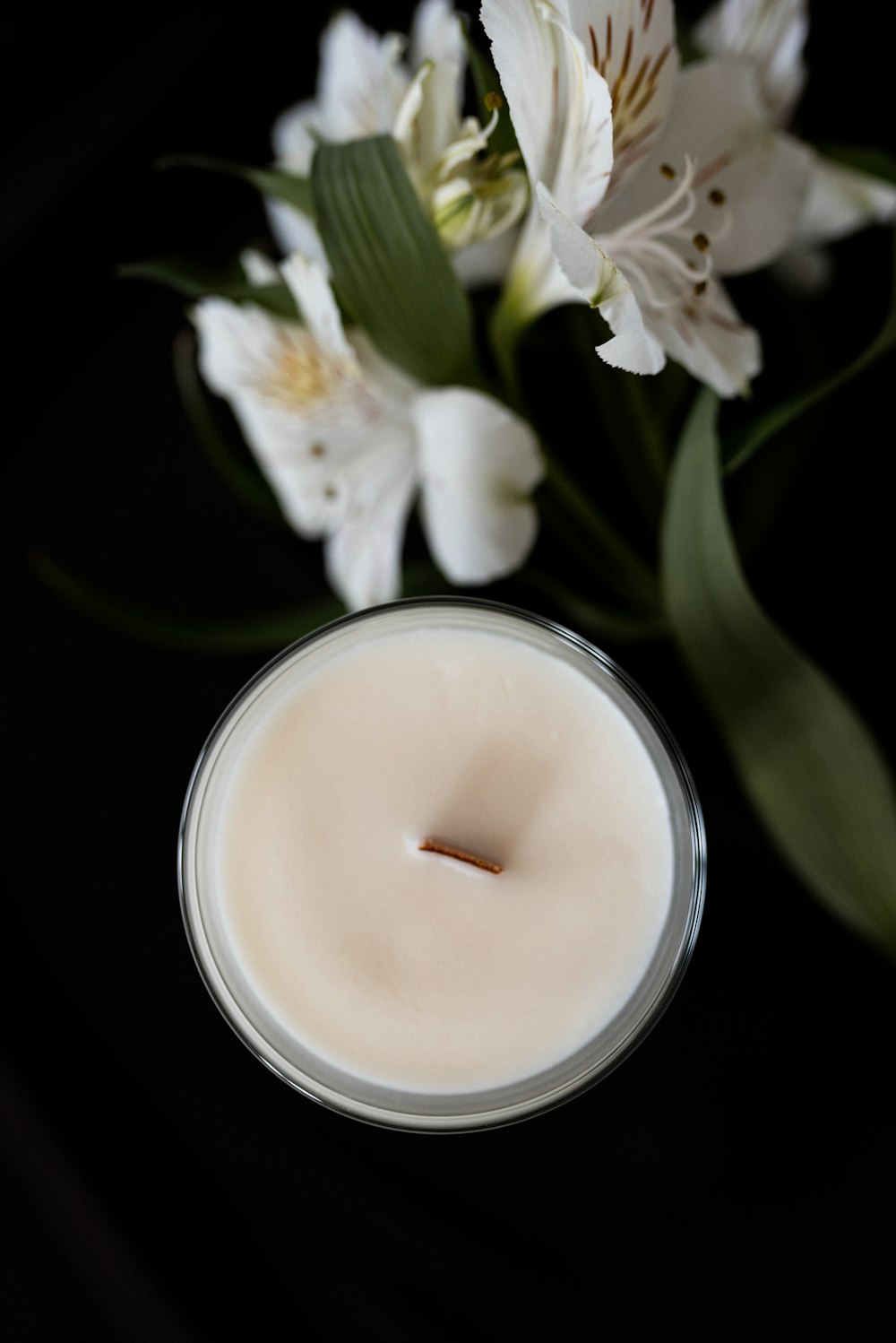 a white candle sitting next to some white flowers