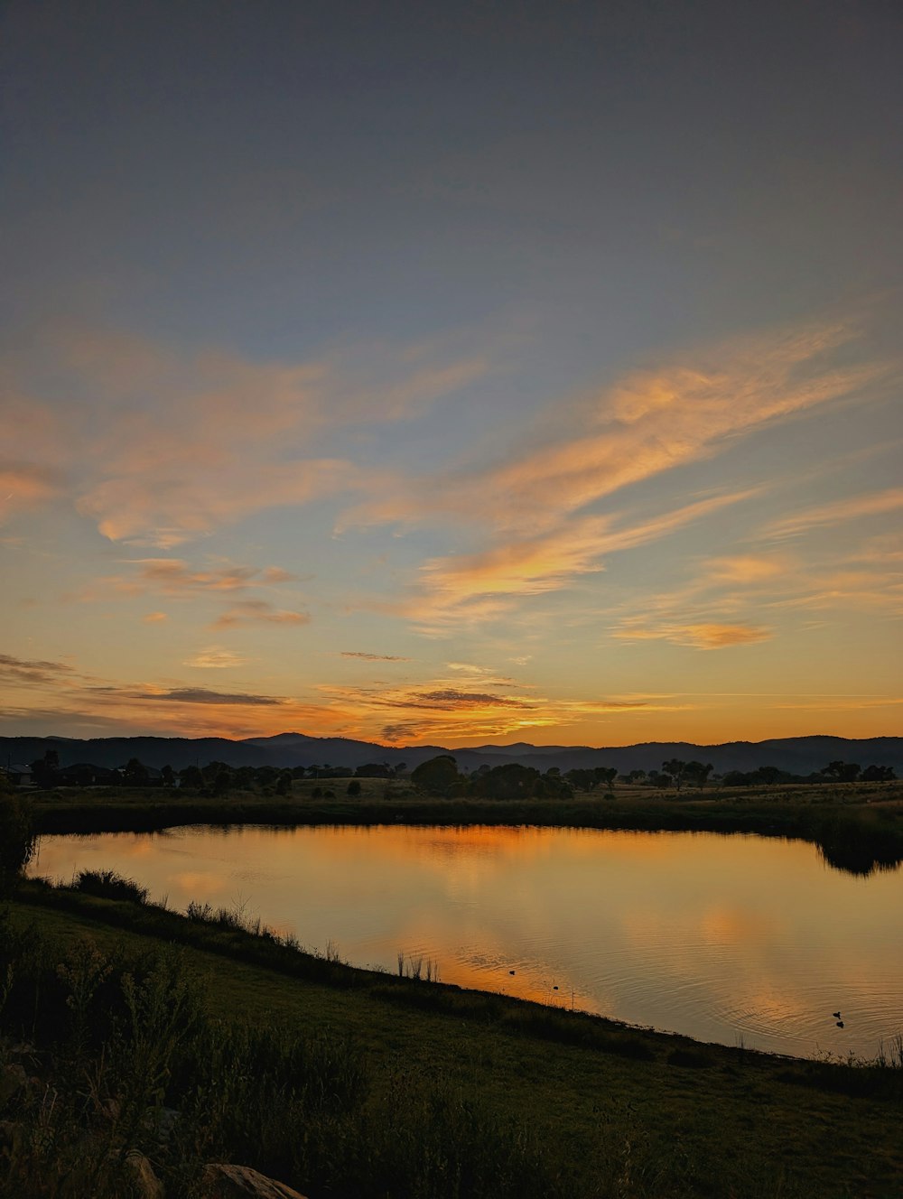 the sun is setting over a small lake