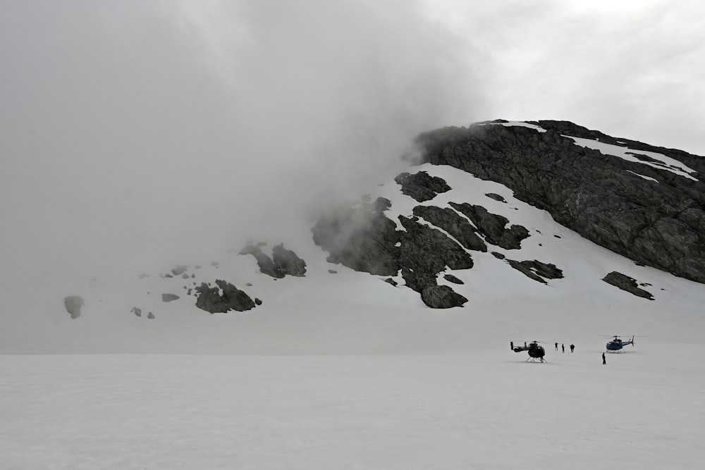 Un grupo de personas de pie en la cima de una ladera cubierta de nieve