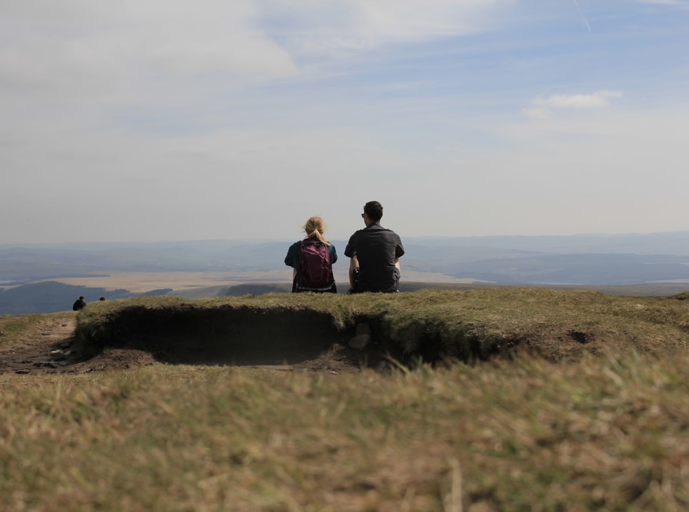 a couple of people sitting on top of a hill