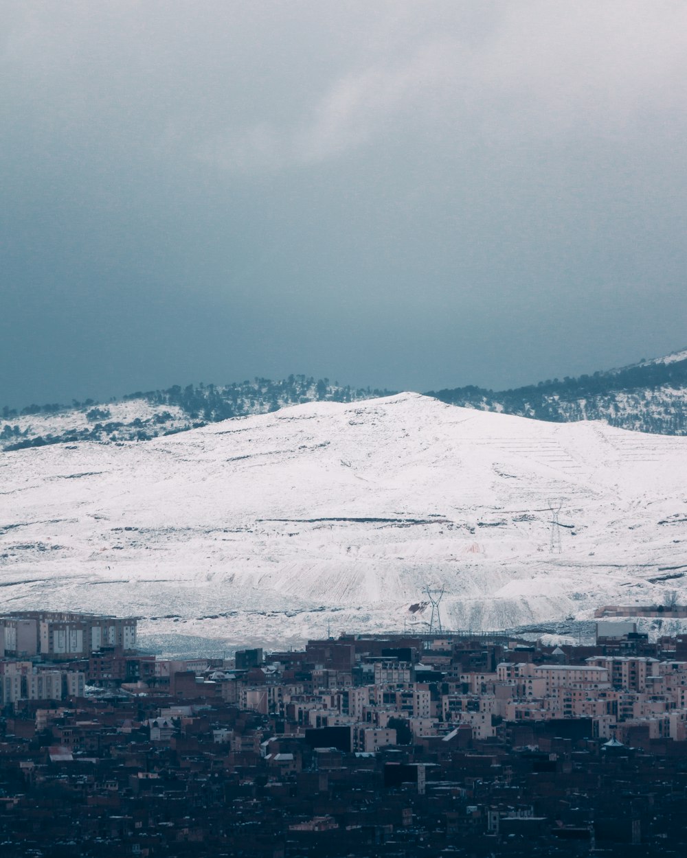 a snowy mountain with a city below it