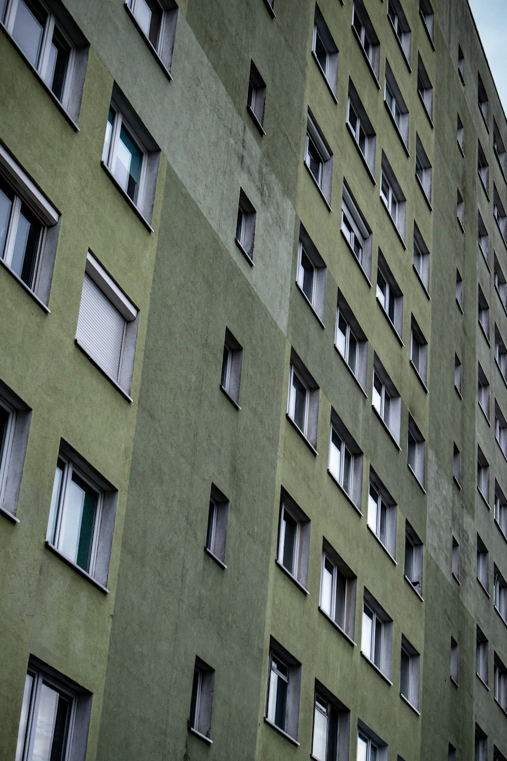 Un edificio alto y verde con muchas ventanas