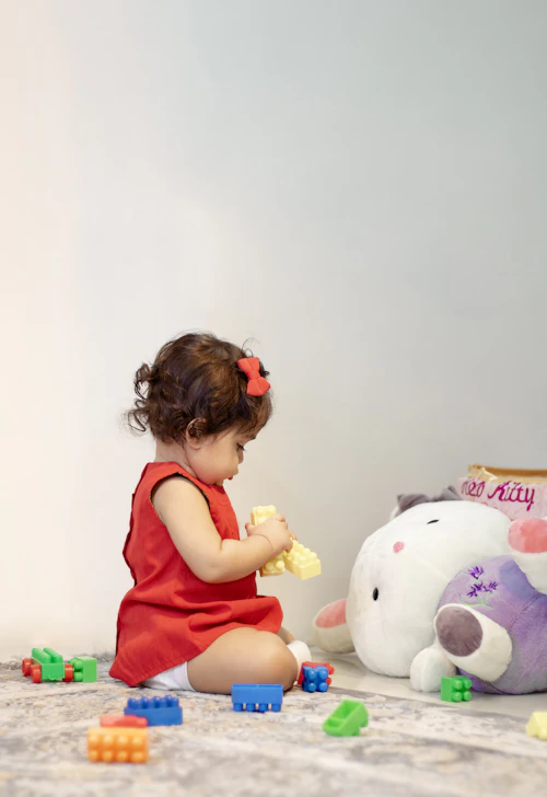 Indian girl in a red dress playing with a stuffed toy during early intervention