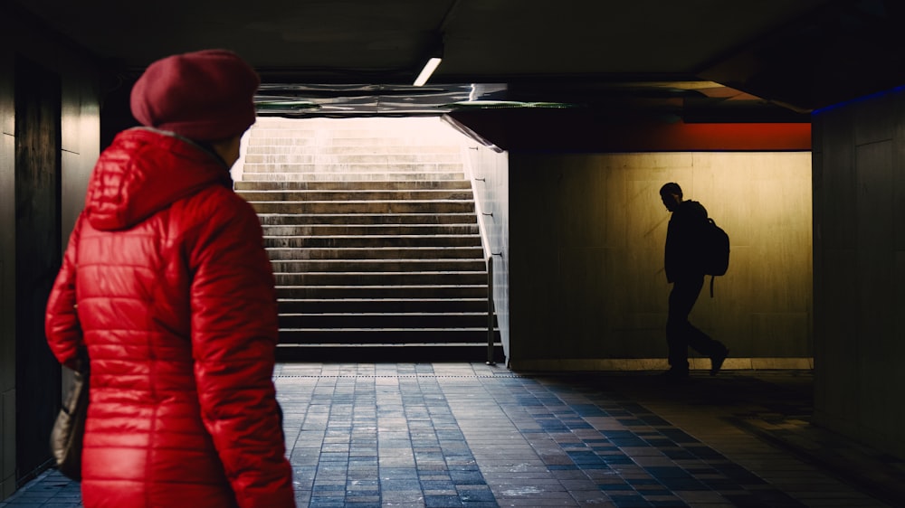 a person in a red coat walking down a hallway