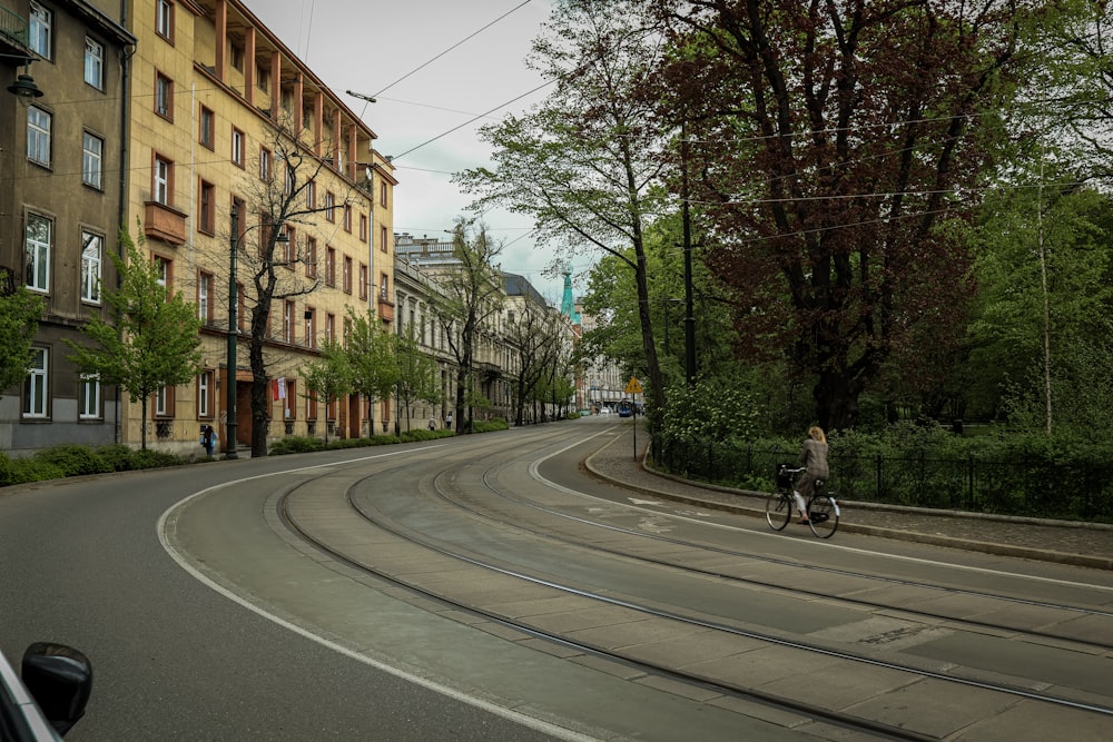 um homem andando de bicicleta por uma rua ao lado de prédios altos