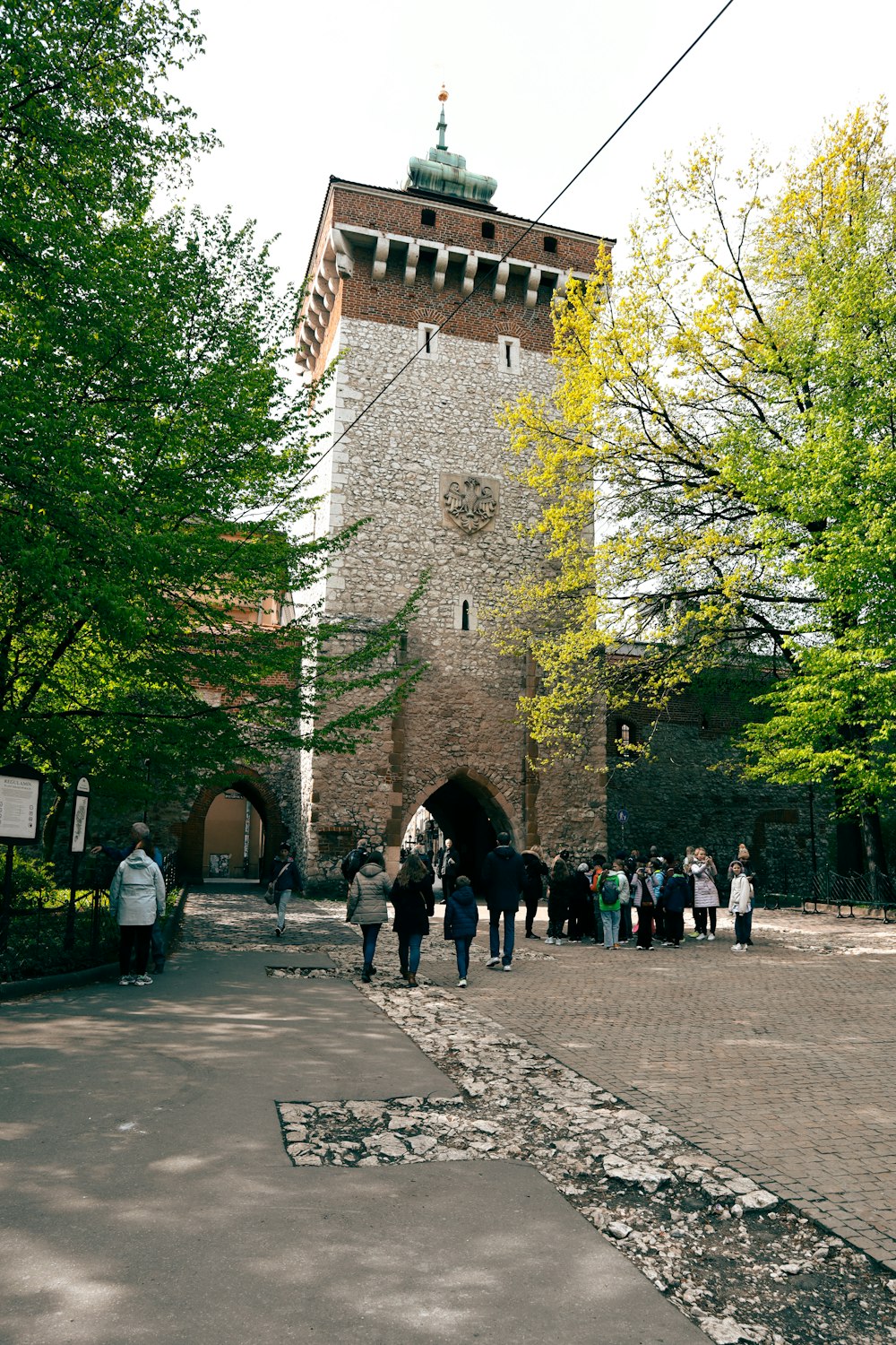 um grupo de pessoas caminhando por uma rua ao lado de uma torre alta