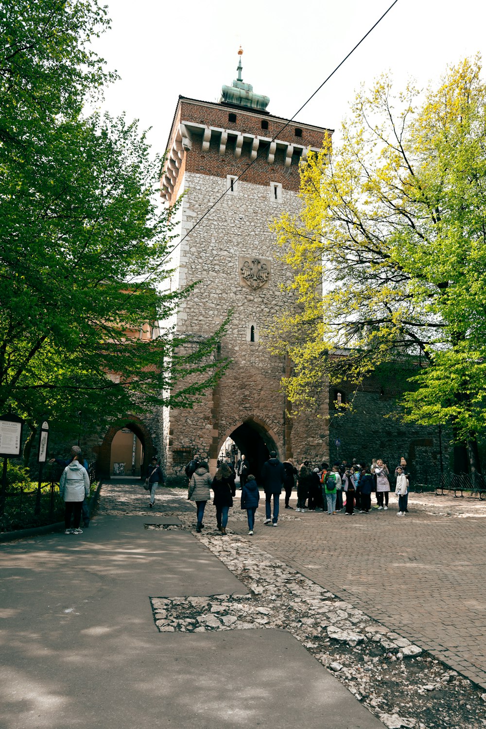 a group of people walking down a street next to a tall tower