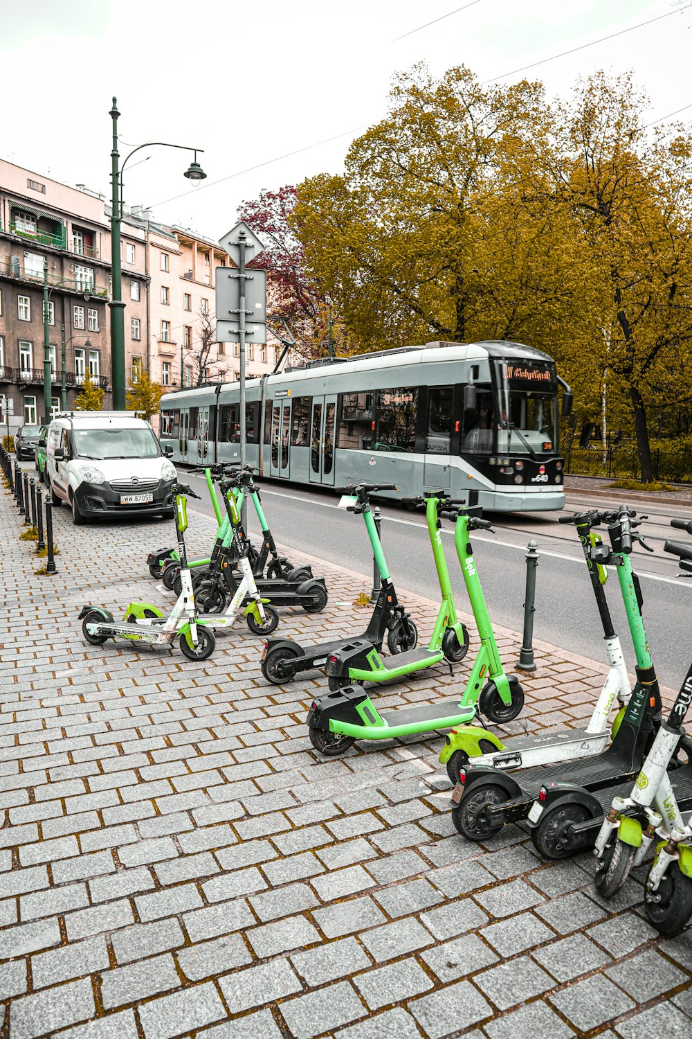 uma fileira de scooters verdes sentados na beira de uma estrada