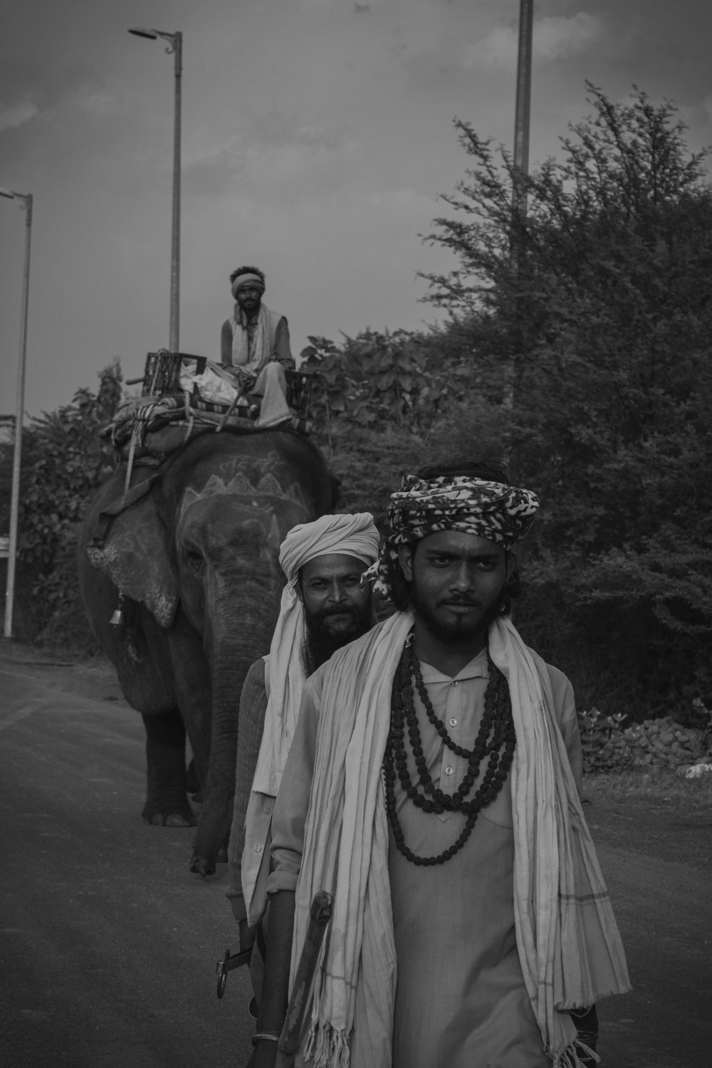 a couple of men walking down a street next to an elephant