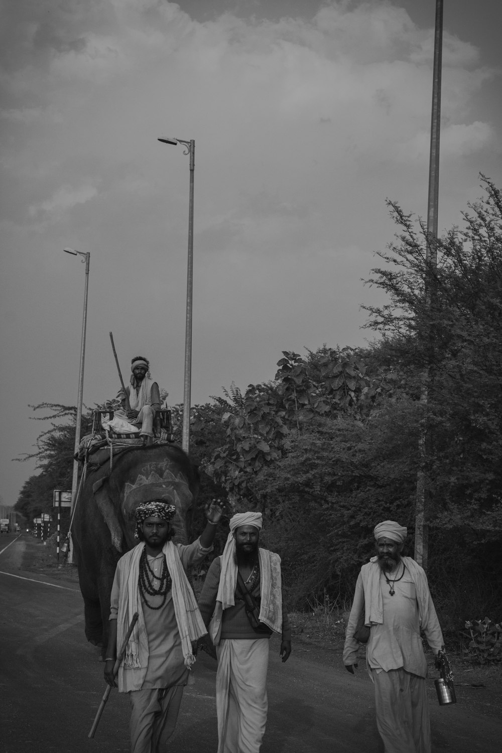 a group of men walking down a street next to an elephant