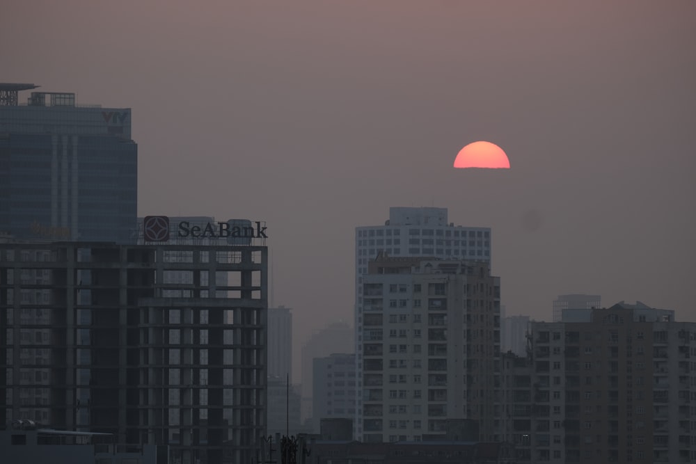 the sun is setting over a city with tall buildings