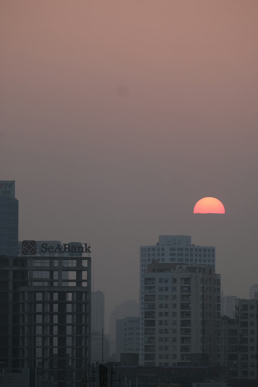 the sun is setting over a city with tall buildings