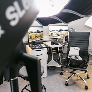 a desk with two computer monitors and a chair