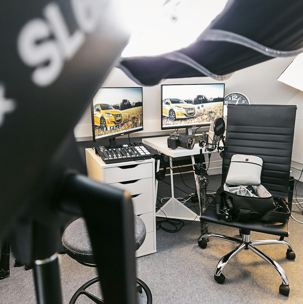 a desk with two computer monitors and a chair