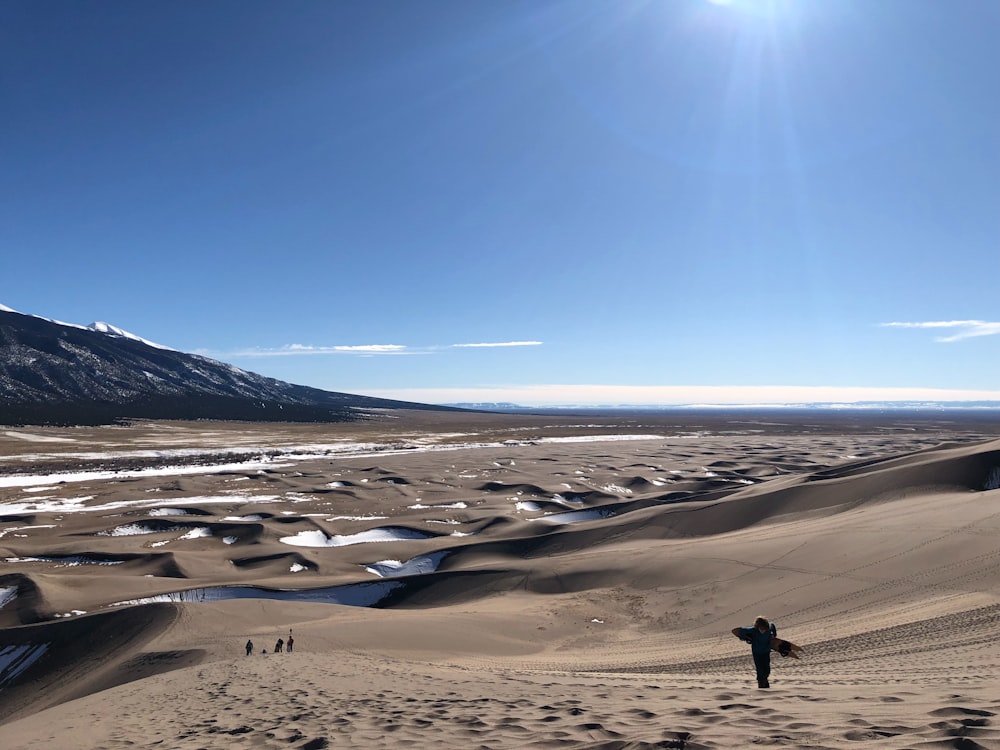 une personne debout au sommet d’une dune de sable