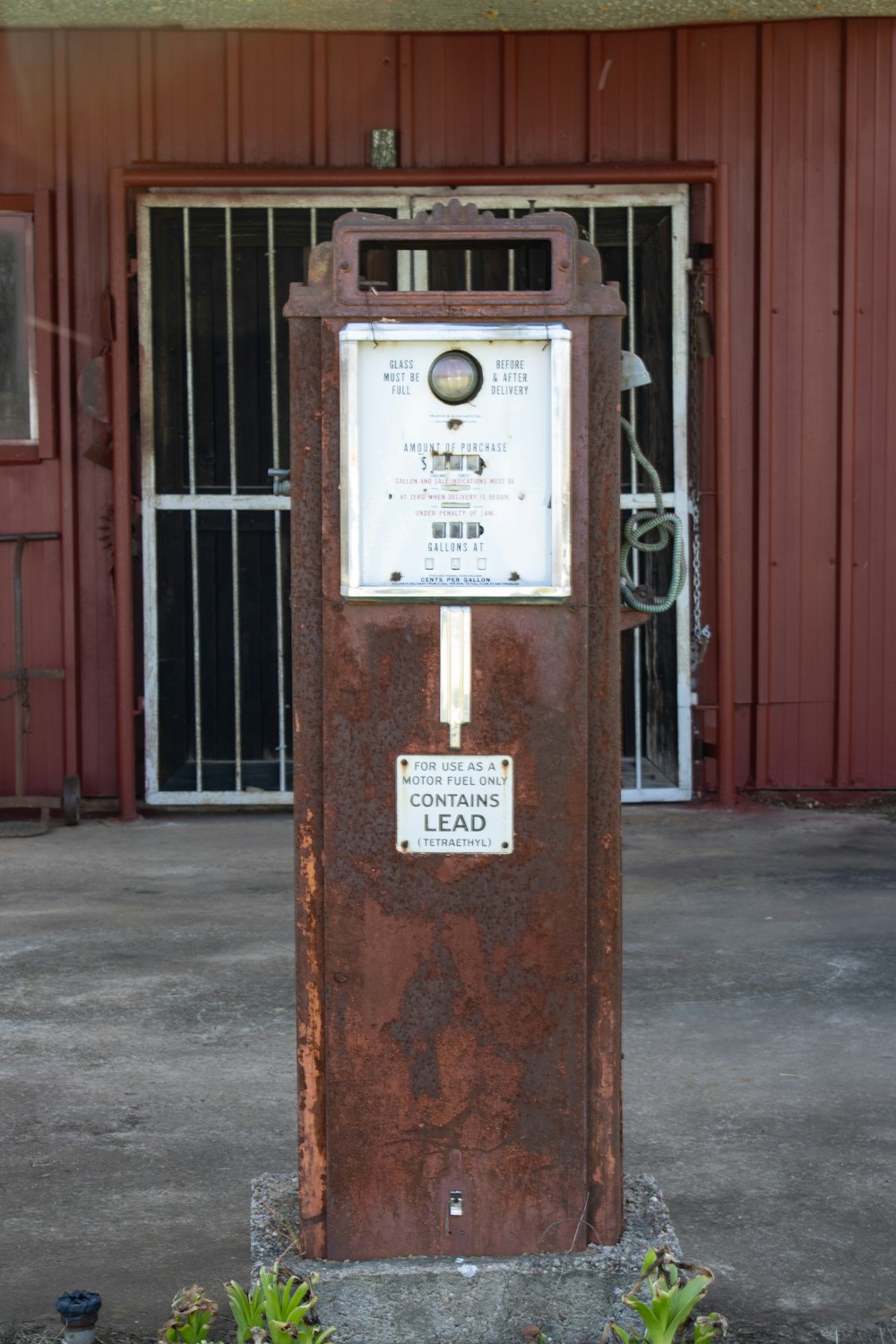 a rusted metal box sitting in front of a red building