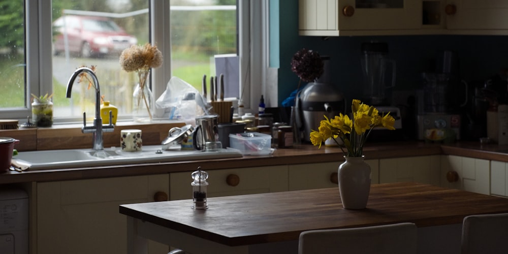 a kitchen counter with a vase of flowers on it