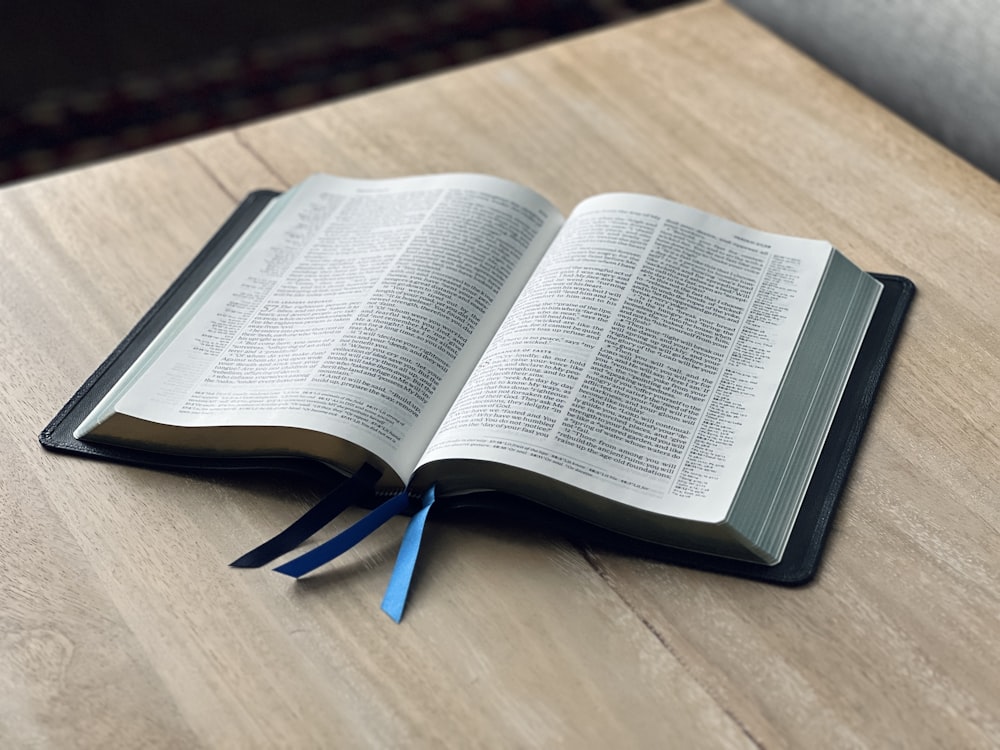 an open book on a table with a blue ribbon