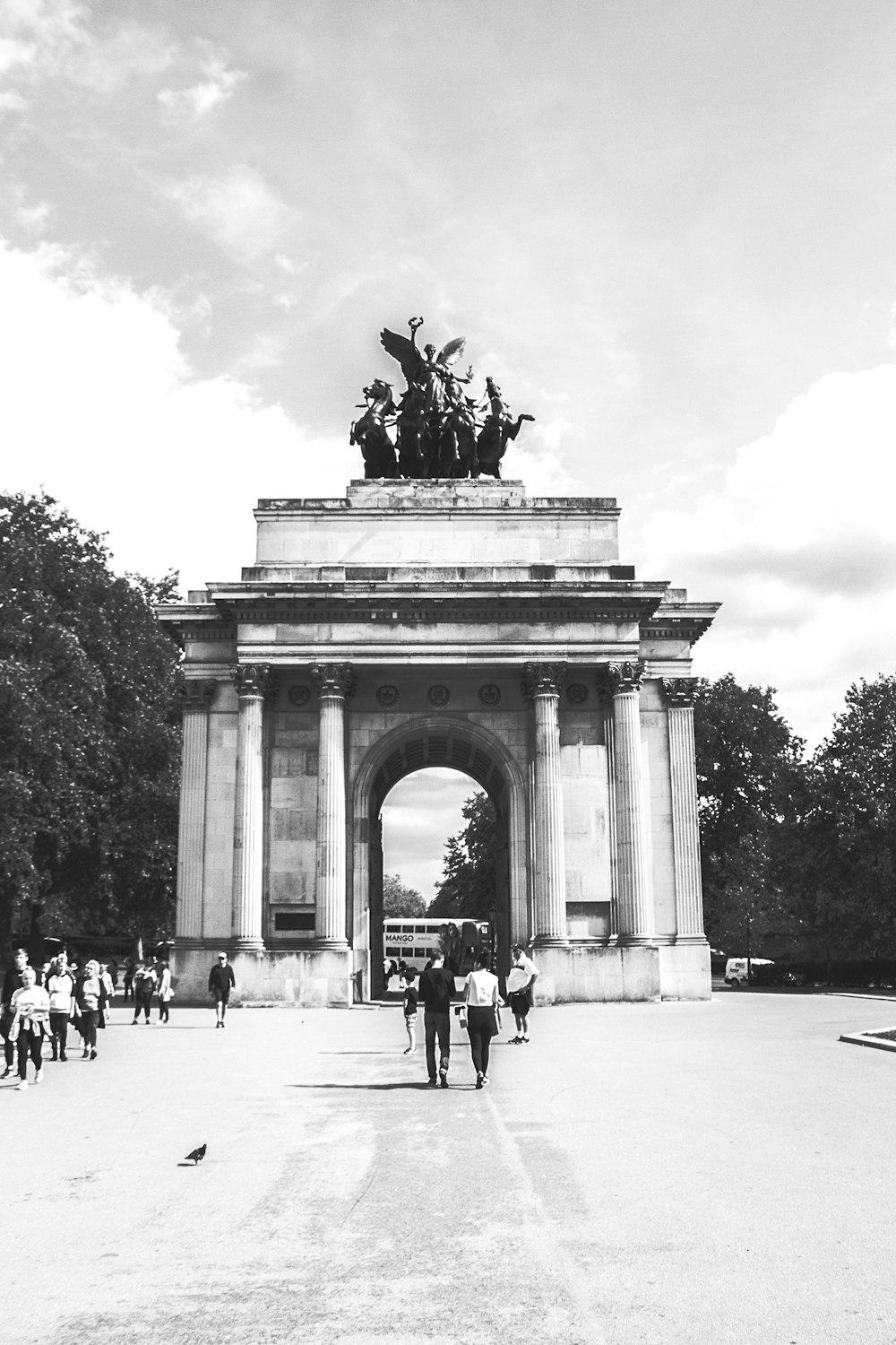a black and white photo of people walking in front of a monument