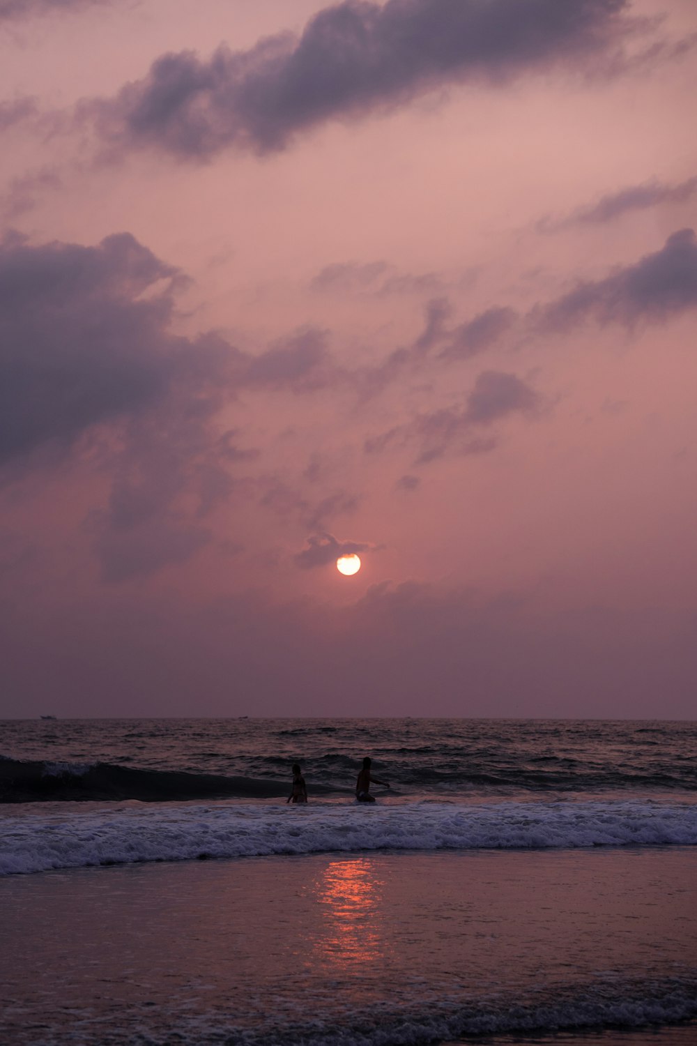 a couple of people standing on top of a beach under a cloudy sky