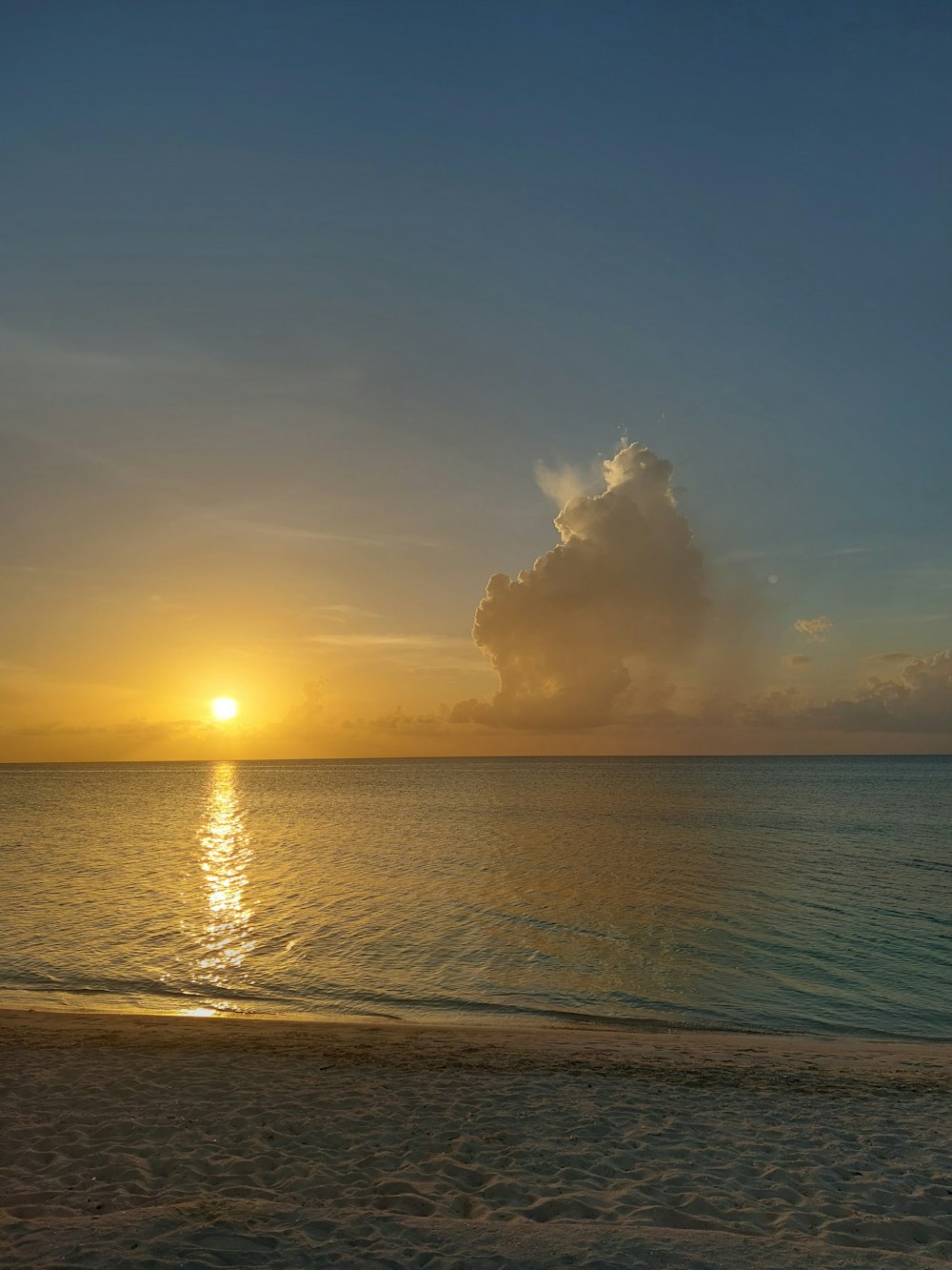 the sun is setting over the ocean on the beach