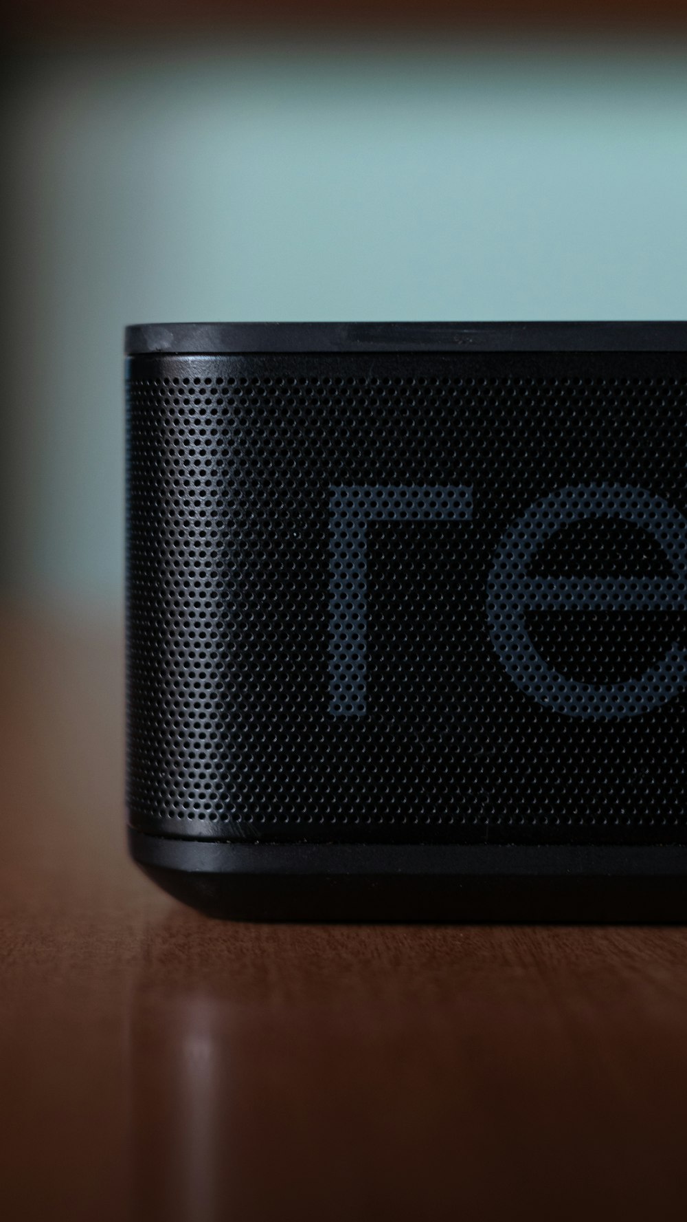 a black speaker sitting on top of a wooden table