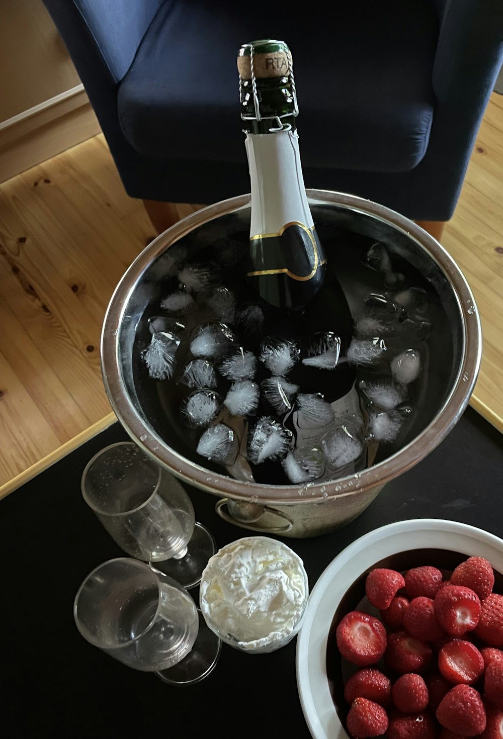 a bottle of wine is being poured into a bowl of ice and raspberries