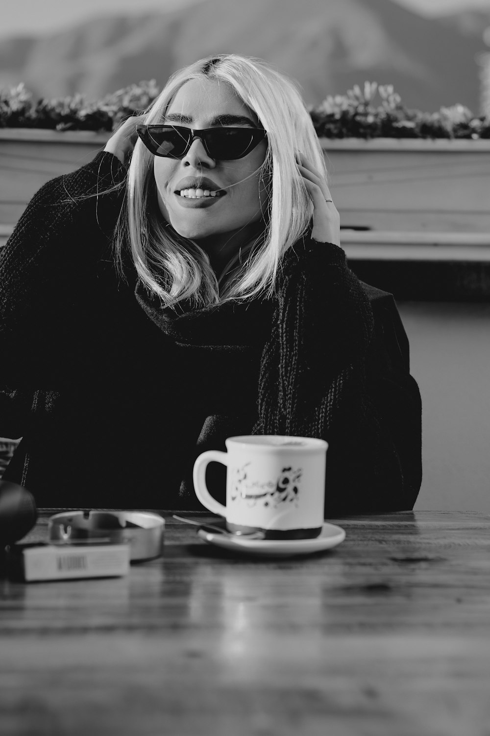 a woman sitting at a table with a cup of coffee