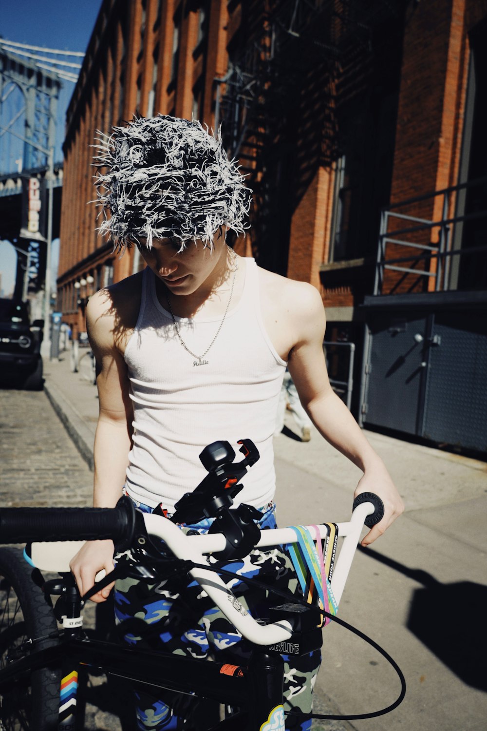 a man standing next to a bike with a bunch of hair on his head