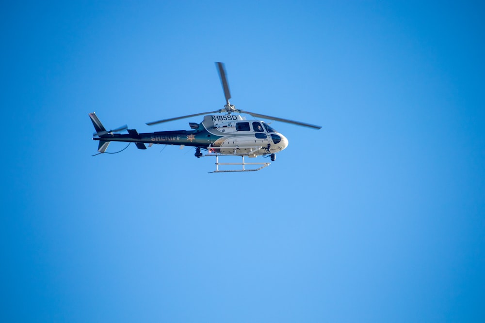 a helicopter flying through a blue sky on a sunny day