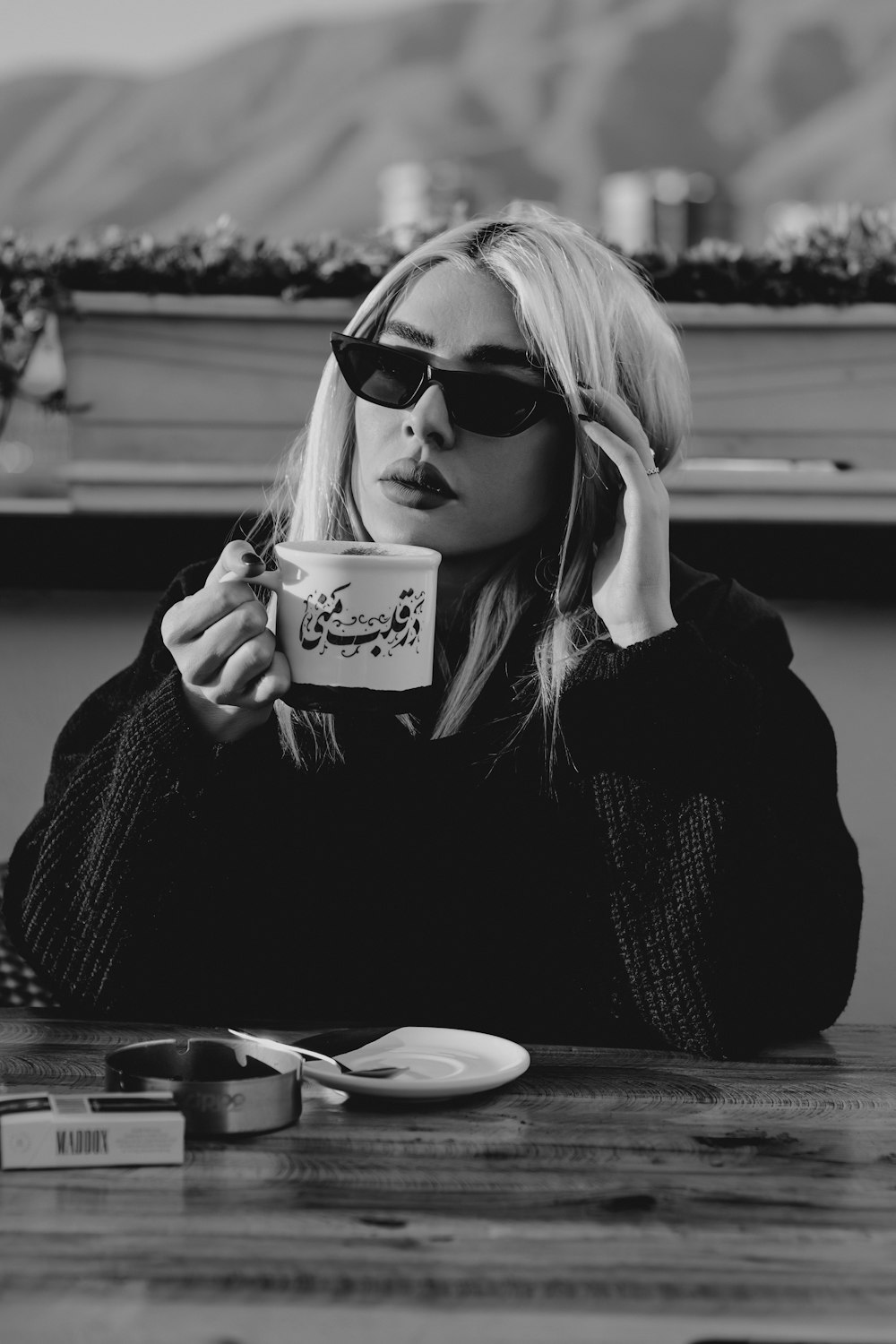 a woman sitting at a table with a cup of coffee