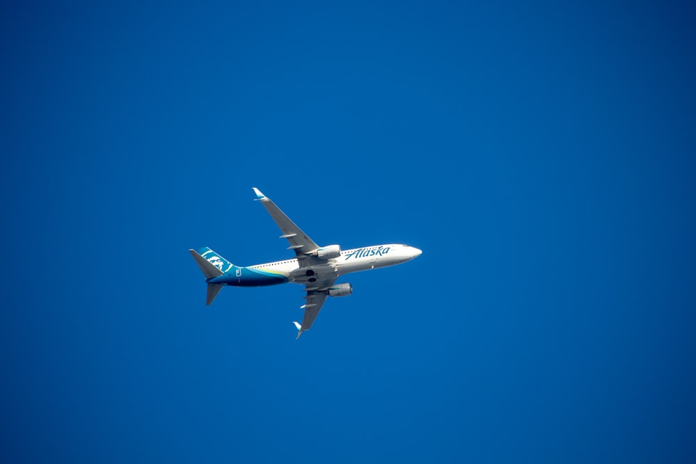 a blue and white airplane flying in a blue sky