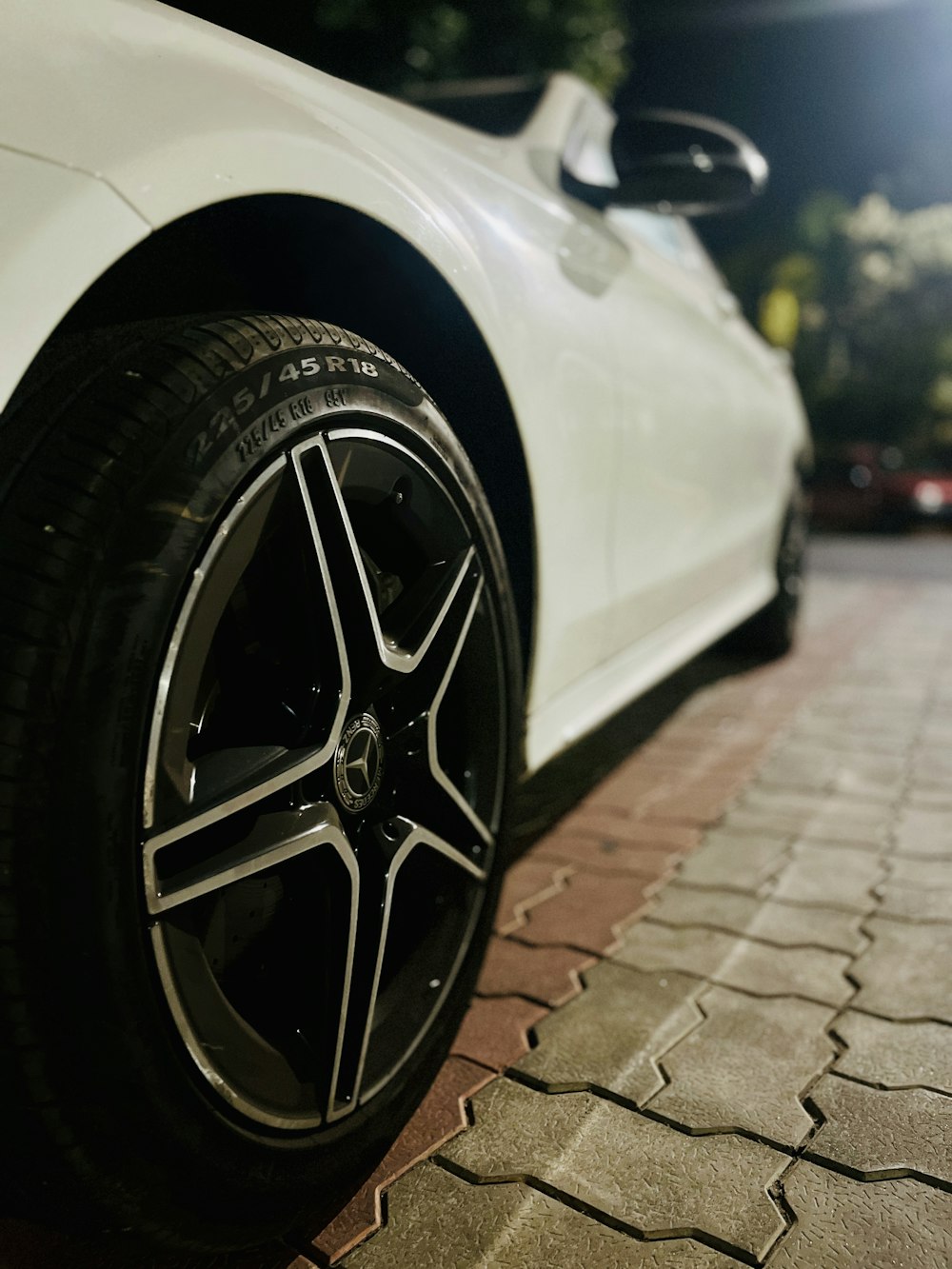 a close up of a white car parked on a brick road