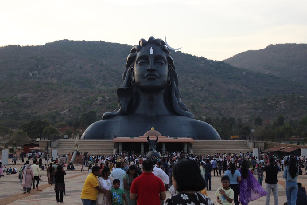 a group of people standing around a large statue