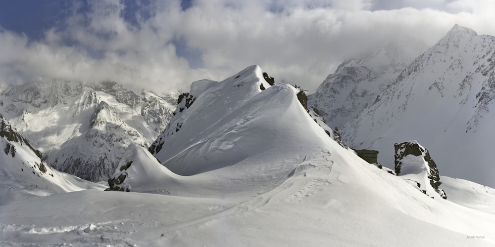 a mountain covered in snow under a cloudy sky