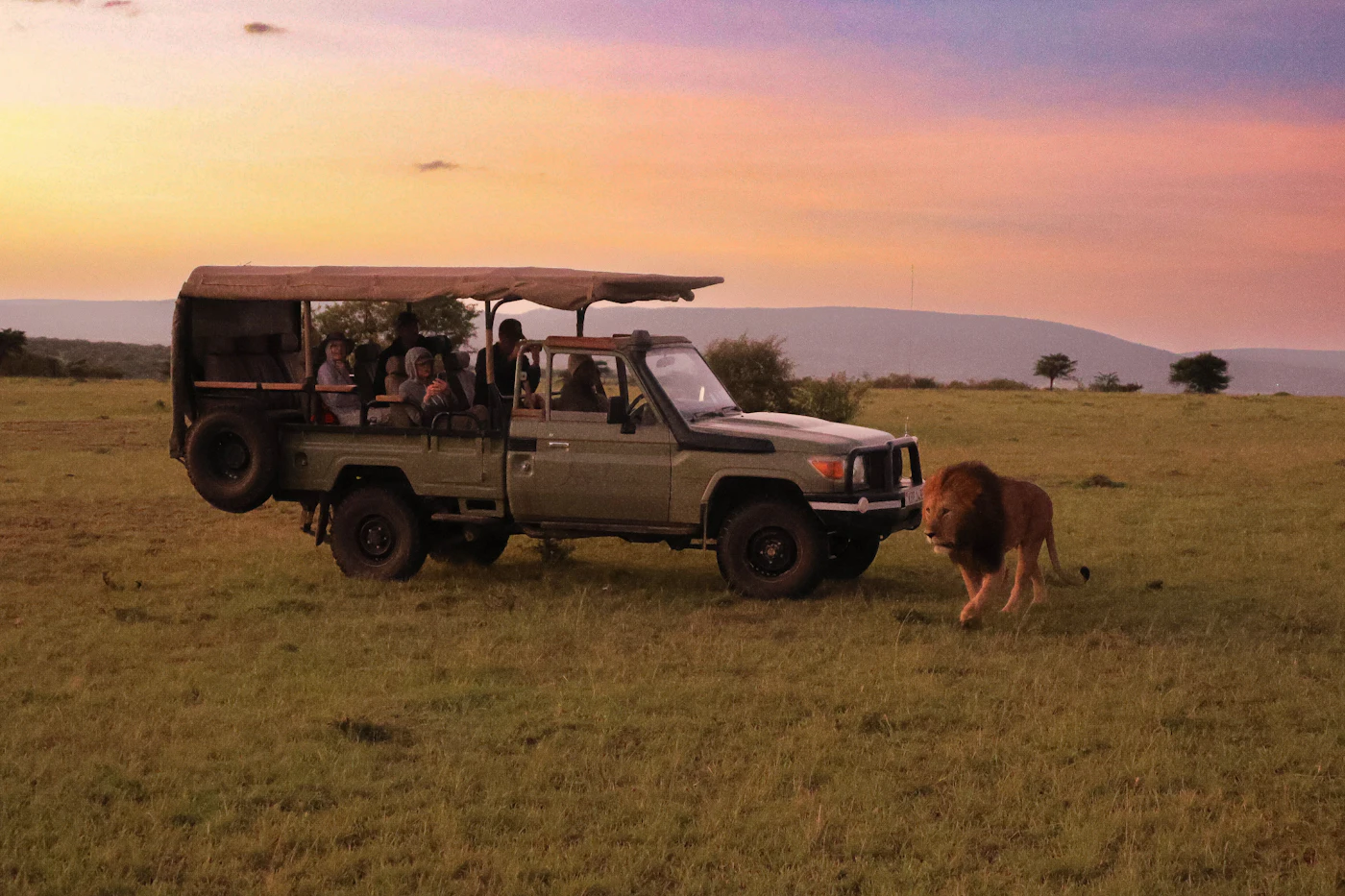 A safari vehicle on an open plain at sunset