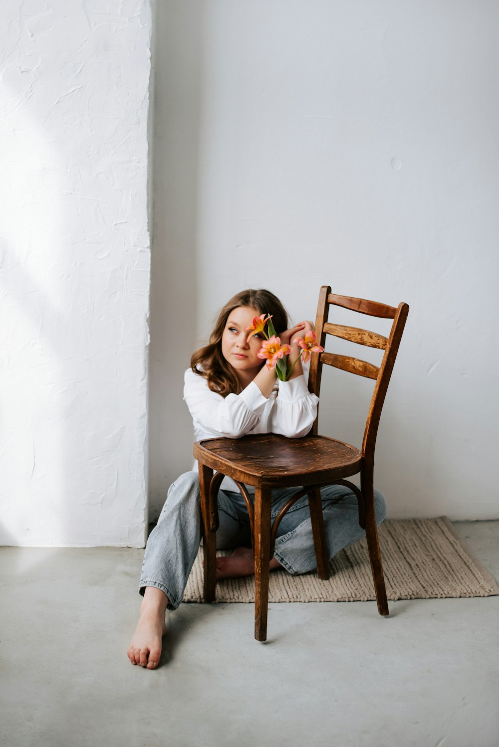 a woman sitting on the floor with a flower in her hand