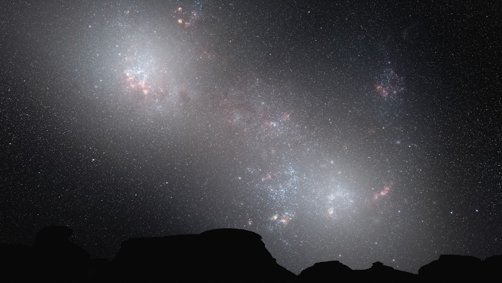 a group of people standing on top of a hill under a sky filled with stars