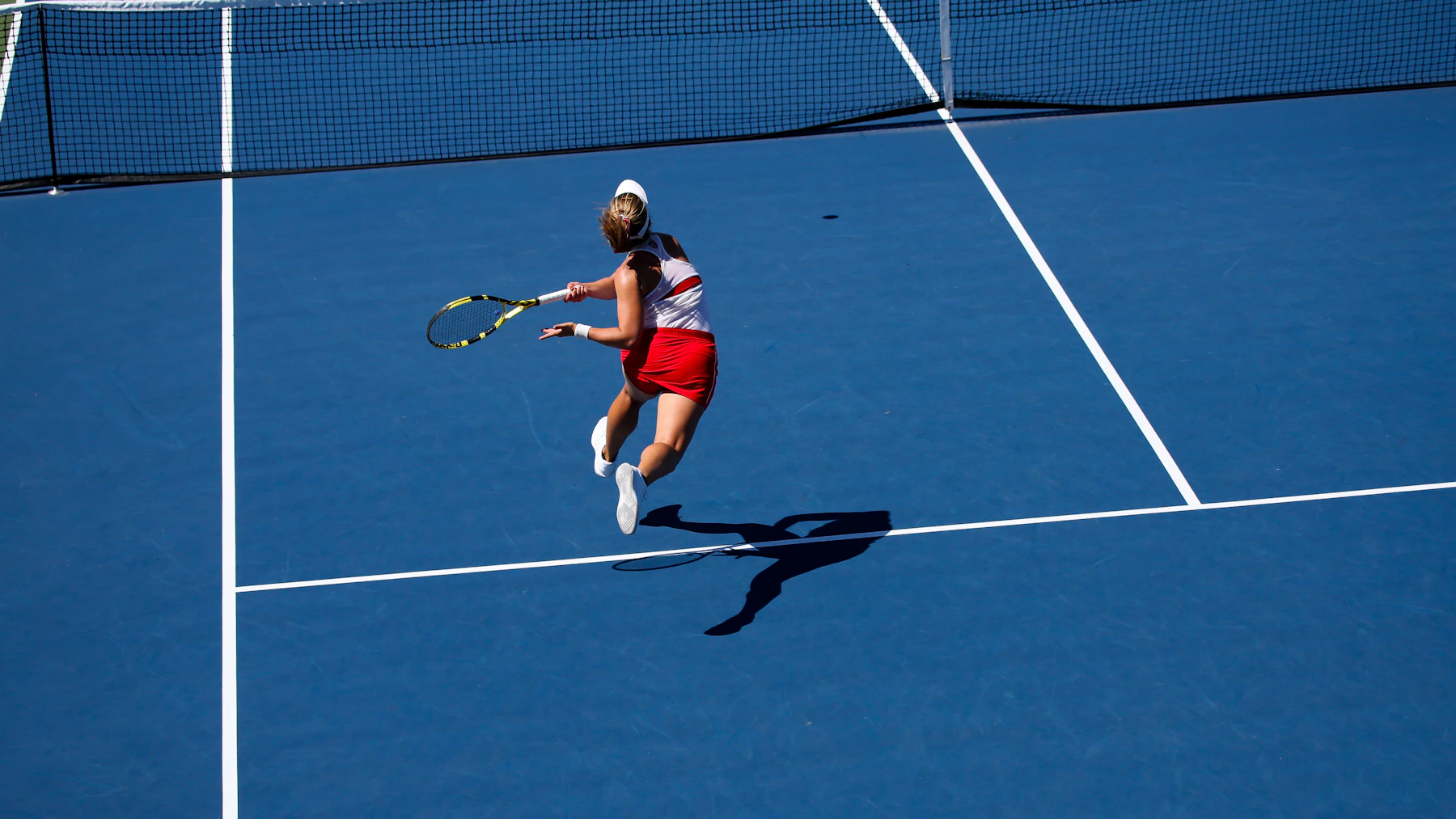 Woman pushing hard off one leg while changing direction on a tennis court.