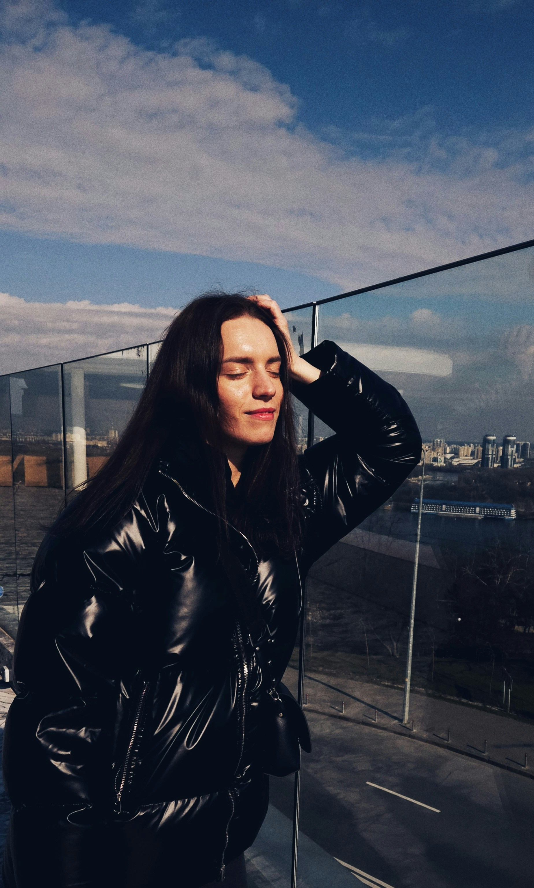 a woman in a black leather jacket standing on a balcony