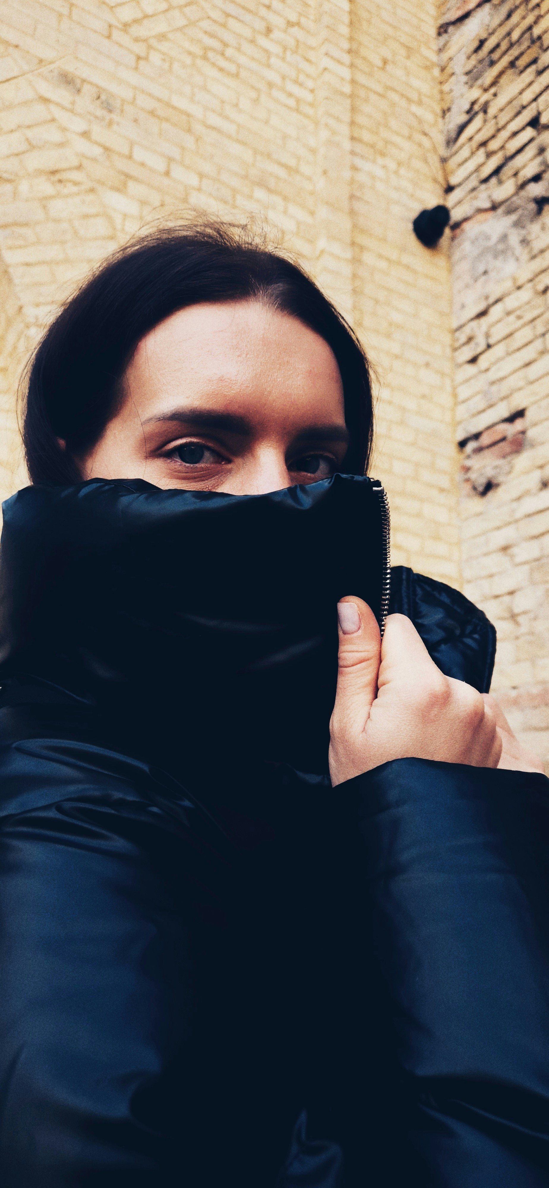 a woman is covering her face with a black jacket