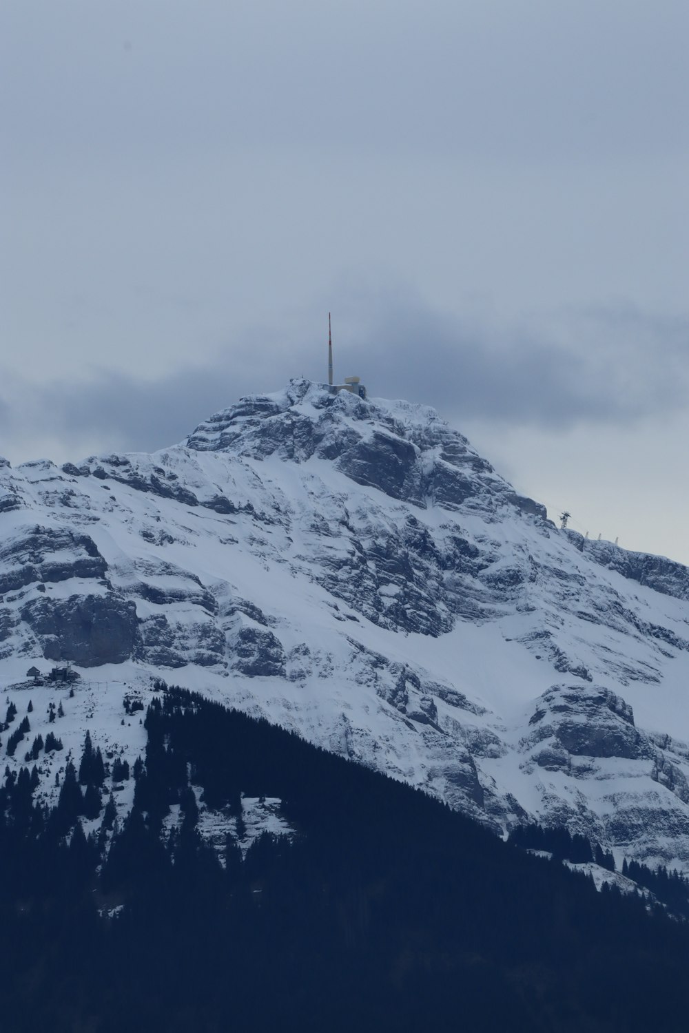 a snow covered mountain with a radio tower on top