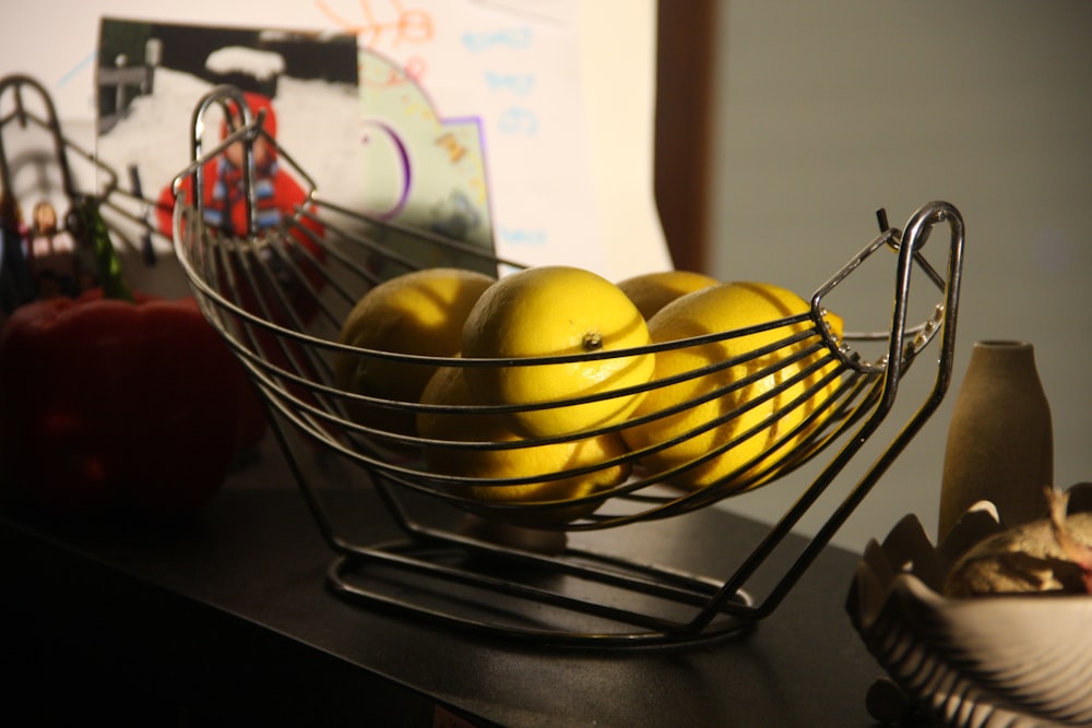 a metal bowl filled with lemons on top of a table