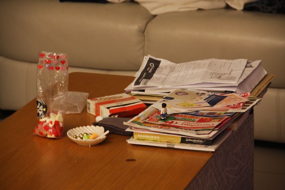 a wooden table topped with magazines and a vase