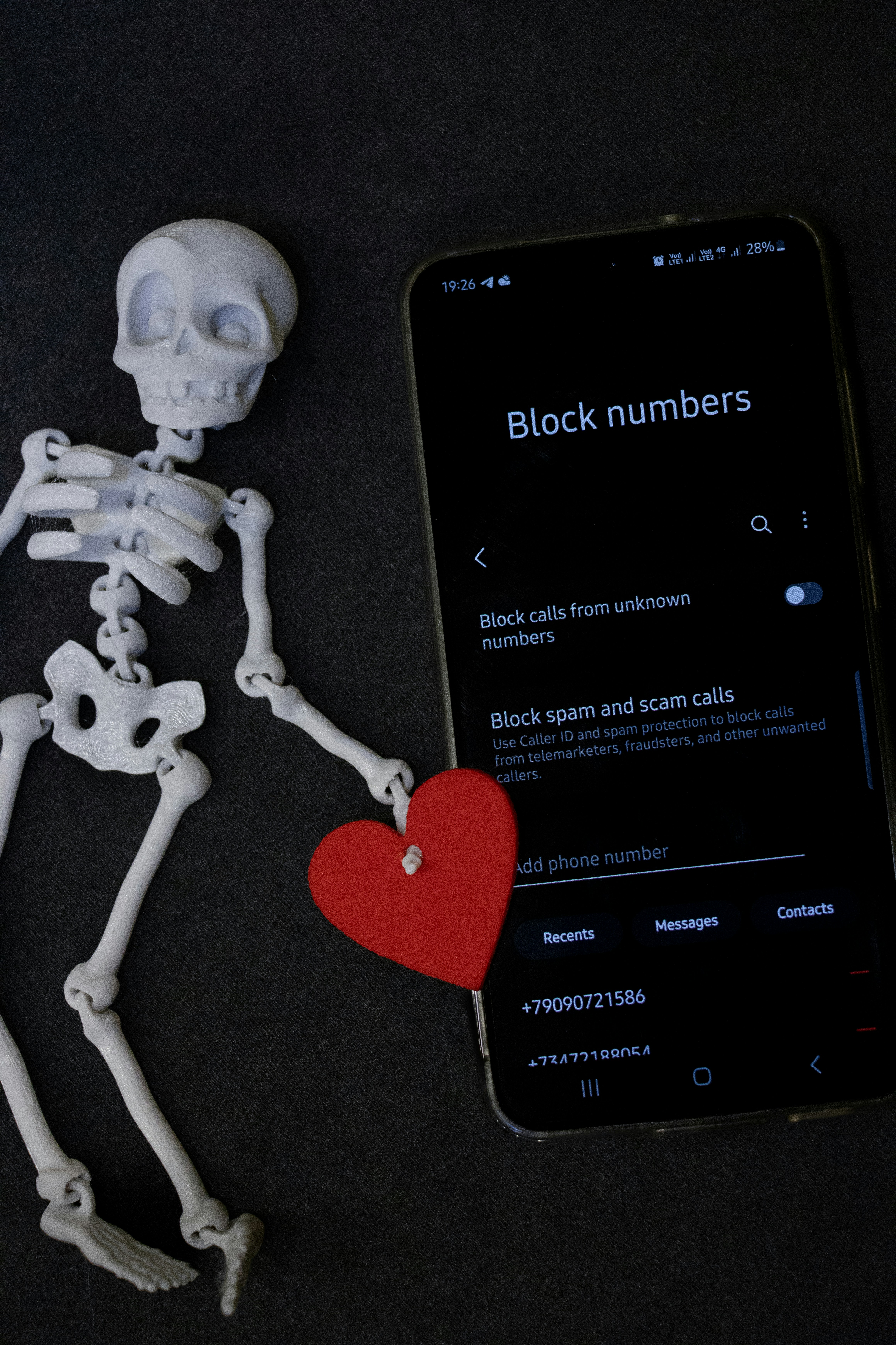 a skeleton holding a heart next to a cell phone