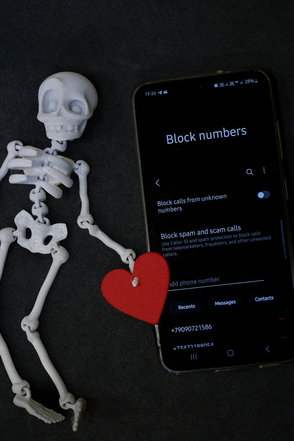 a skeleton holding a heart next to a cell phone