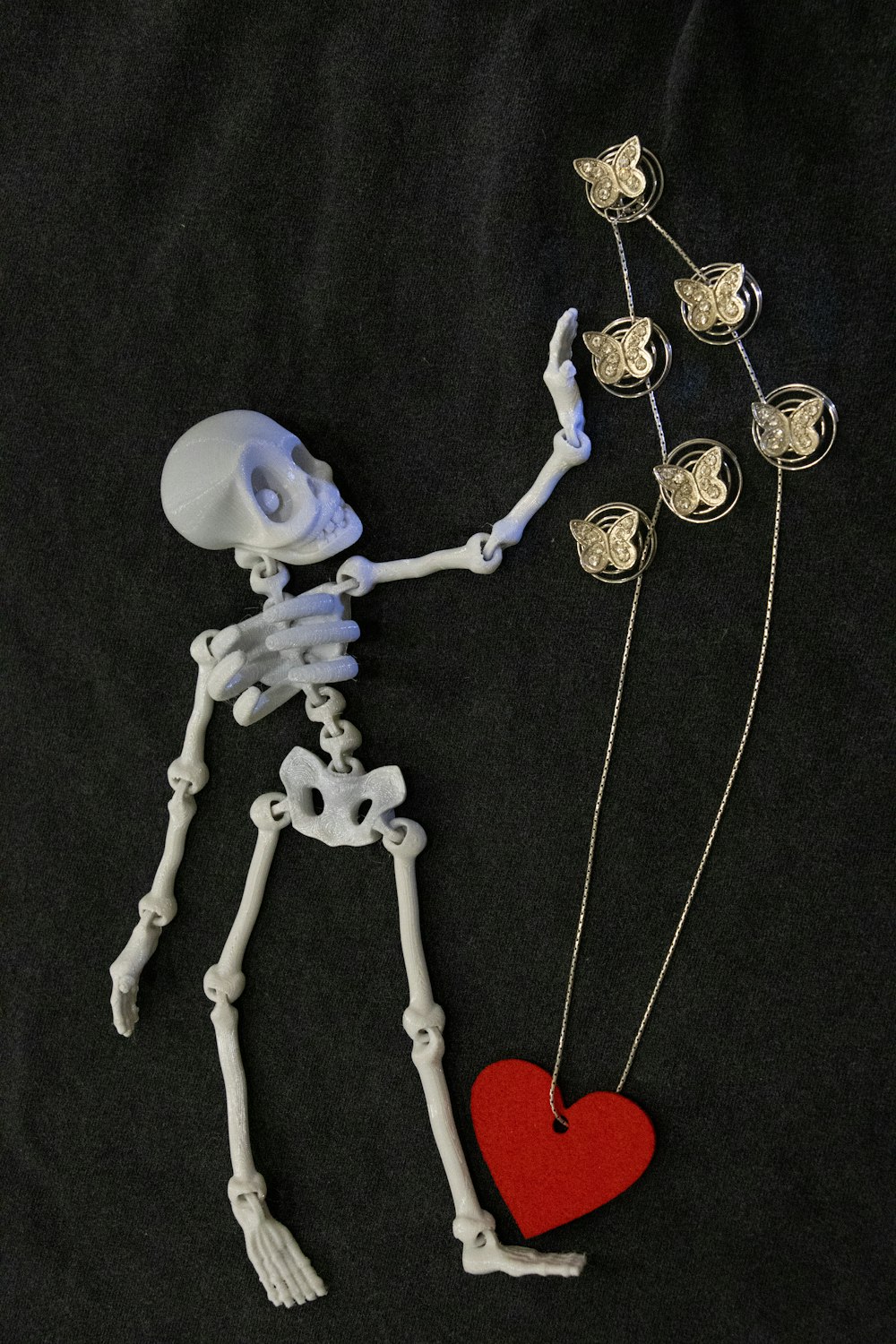 a skeleton holding a red heart on a black background