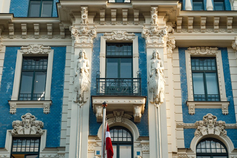 Blue and white Art Nouveau facade with sculptures and a Latvian flag in Riga