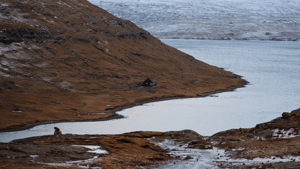 a man standing on top of a mountain next to a lake